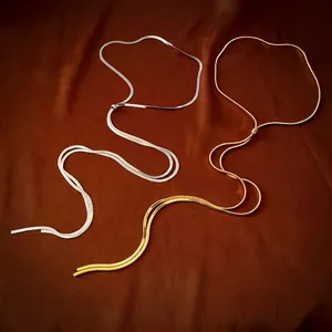 Elegant gold and silver titanium steel snake chain necklaces on dark silk background