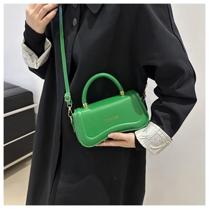 Close-up of green leather handbag with fashion lettering and thick handle detail