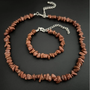 Detailed shot of brown goldstone necklace and bracelet set on black leather background