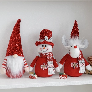 Three Christmas plush ornaments featuring Santa gnome, snowman, and reindeer on a white shelf