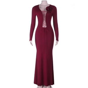 Détail d'une robe de soirée bordeaux à manches longues avec décolleté lacé et fleur d'épaule