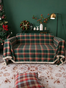 Detail of red and green plaid sofa cover with white fringe and Christmas decor