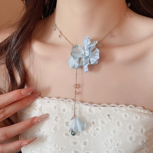 Detailed close-up of light blue fabric flower necklace with crystal beads on golden chain