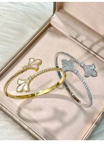 Detail view of gold and silver fan-shaped bangles with white shell and zircons