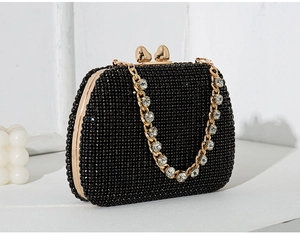 Detail of black evening clutch with heart clasp and crystal-embellished gold chain