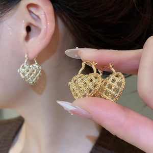 Detail of golden heart-shaped hoop earrings with intricate hollow woven metal texture