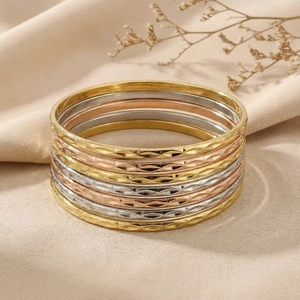 Detail of stacked titanium steel bangles in gold, silver and rose gold with ripple texture