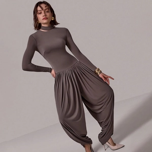 Detail view of taupe long sleeve jumpsuit featuring waist pleats and side slit design