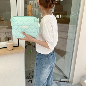 Quilted heart pattern makeup bag in mint green shown in a trendy street-style cafe setting