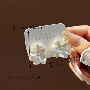 Detail view of 2.4cm white daisy stud earrings with pearlescent layered petals and size text