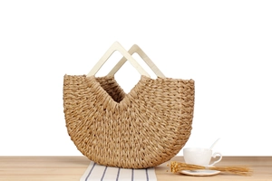 Detail of woven straw handbag with gold thread, wooden handle and holiday beach vibe