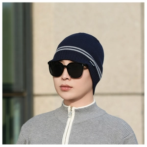 Close-up of a navy blue winter knit visor cap with grey stripes and small woven logo