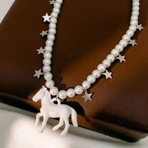 Detailed macro view of beaded pearl necklace with silver stars and colorful horse pendant