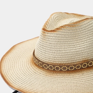 Détail de chapeau de paille avec bords vieillis marrons et ruban de strass doré