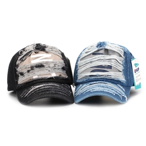 Close-up of distressed denim baseball caps showing frayed holes and vintage texture
