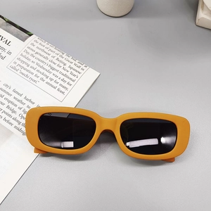 Detail of trendy rectangle sunglasses with bold orange frames and dark lenses