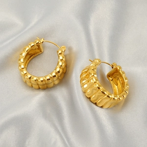 U-shaped stainless steel earrings with gold rippled texture on soft grey silk