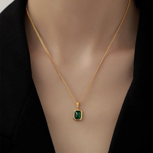 Elegant gold necklace with emerald square pendant shown on a model's neck