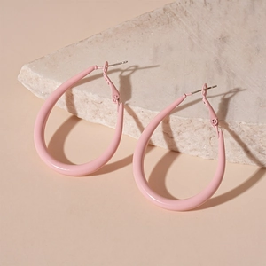 Detail view of pink matte teardrop hoop earrings on a minimalist stone display stand