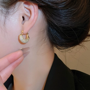 Close-up of elegant gold huggie earrings with shimmering pave-set cubic zirconia on model
