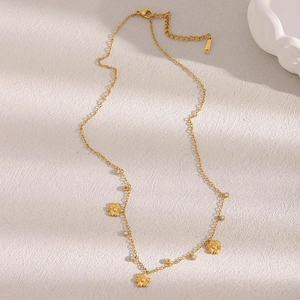Flat lay of gold plated flower necklace with zircon accents on textured fabric