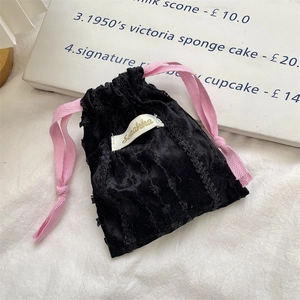 Dettaglio della borsa in velluto nero con coulisse rosa ed etichetta bianca Suikka