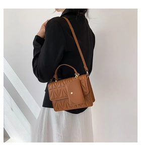 Detail view of caramel brown quilted crossbody bag with matching mini pouch attachment
