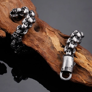 Detail of vintage skull bracelet in aged stainless steel on a dark wood block
