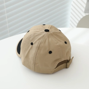 Two-tone khaki and black baby baseball cap with adjustable metal buckle on white surface