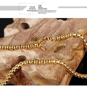 Close-up of golden stainless steel box chain necklace with lobster clasp on wood