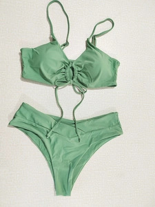 Detailed flat lay of sage green two-piece bikini set with ruched bandeau top and V-cut bottom