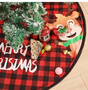 Detail of red and black plaid Christmas tree skirt with reindeer and Merry Christmas text