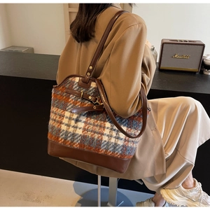 Detail of checkered tweed tote bag with premium brown leather straps and reinforced base