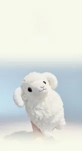 Close-up of white plush lamb toy with soft sherpa wool texture and curved horns