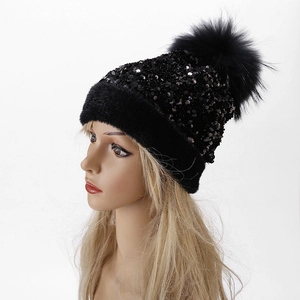 Detail view of winter black knit beanie with sequins and fluffy faux fur pompom
