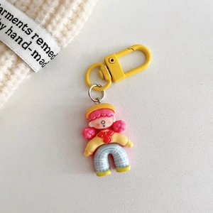 Detail of cute cartoon girl keychain with pink hair and yellow clasp on soft beige background