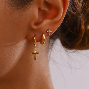 Set di orecchini in oro con ciondoli a croce e strass indossati da una modella