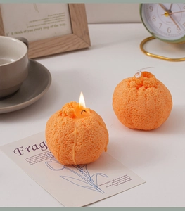 Detalle de velas aromáticas con forma de naranja realista, textura fina y llama encendida