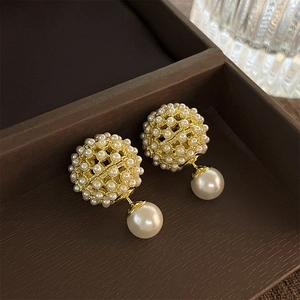 Detail of gold-plated cluster pearl earrings with hollow sphere inside a jewelry box