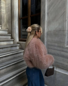 Dettaglio della giacca rosa in finta pelliccia e accessorio floreale per capelli su modella