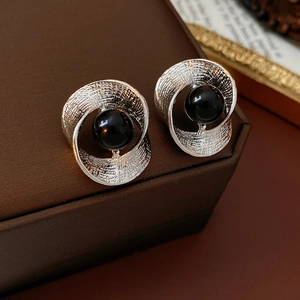 Detailed shot of silver textured hoop earrings with black bead on a vintage jewelry box