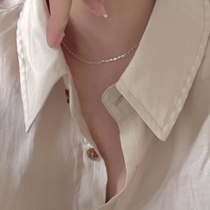 Close-up of a minimalist 925 sterling silver chain necklace worn by a model on linen