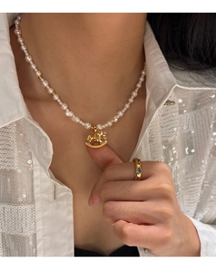 Detail of gold horse pendant pearl necklace and vintage gemstone ring worn by model
