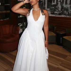 Detail view of a white halter neck deep V-neck maxi dress with an elegant flowing skirt
