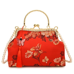 Close-up of red shell bag with gold floral embroidery, rhinestone frame and tassel