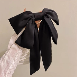 Grande pince à cheveux élégante en satin noir avec longs rubans sur fond doux