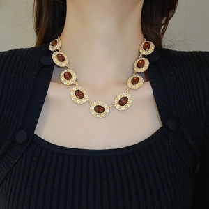 Close-up of a vintage gold floral necklace featuring amber oval gemstones and micro-diamonds