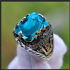 Detail of vintage men's ring with rectangle blue gemstone and ornate silver-gold carving