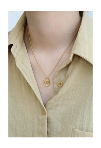 Close-up of a high-quality gold irregular oval pendant necklace on a linen shirt