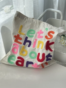 Close-up of colorful towel embroidery letters on off-white cotton canvas tote bag
